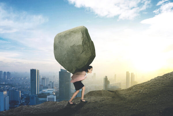 A businesswoman carries a boulder up a hill
